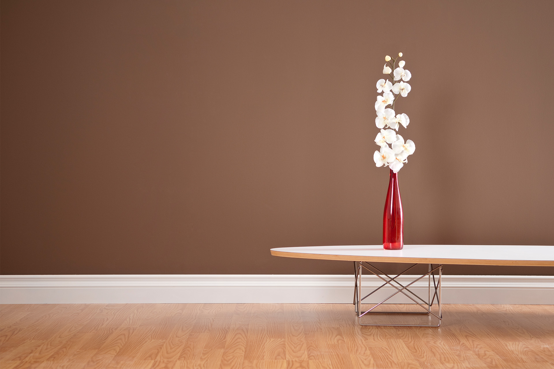 Weiße Sockelleisten mit roter Vase auf Holzboden